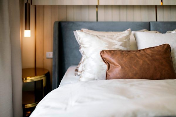 Closeup of new bed comforter with decorative pillows, headboard